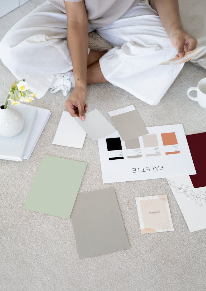 services-04 Designer sits on carpet with color palettes and samples, planning creative project.